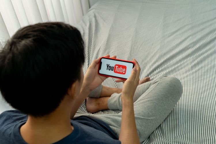 Young man holding a phone watching YouTube